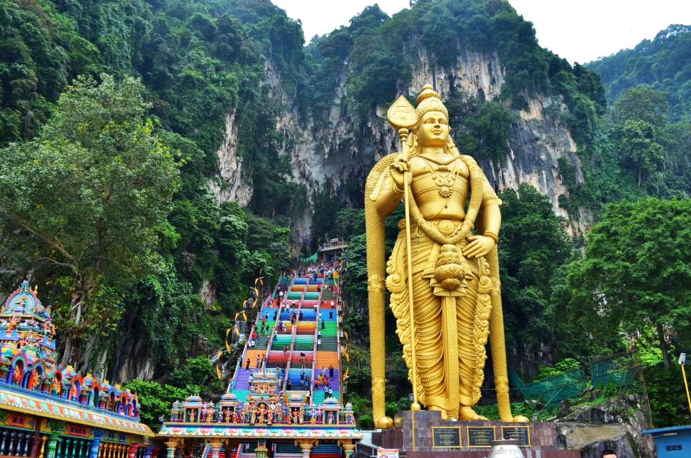 God Murugan statue and iconic Batu Caves entrance steps in the background
