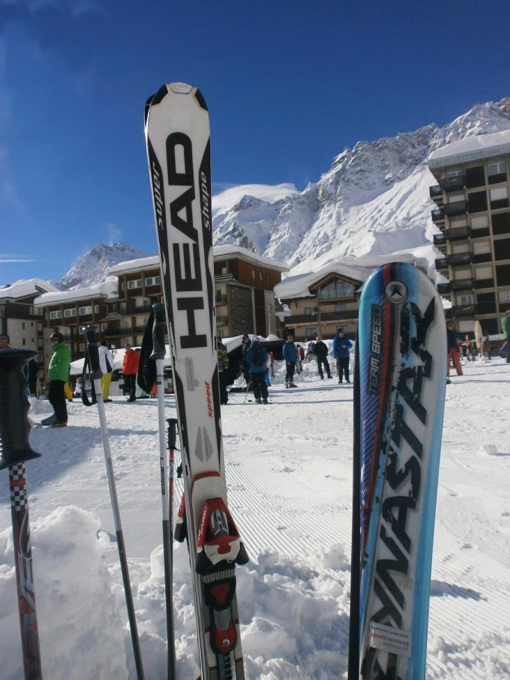 Ski break in sunny Cervinia. our skis left on snow with crowd and mountains behind