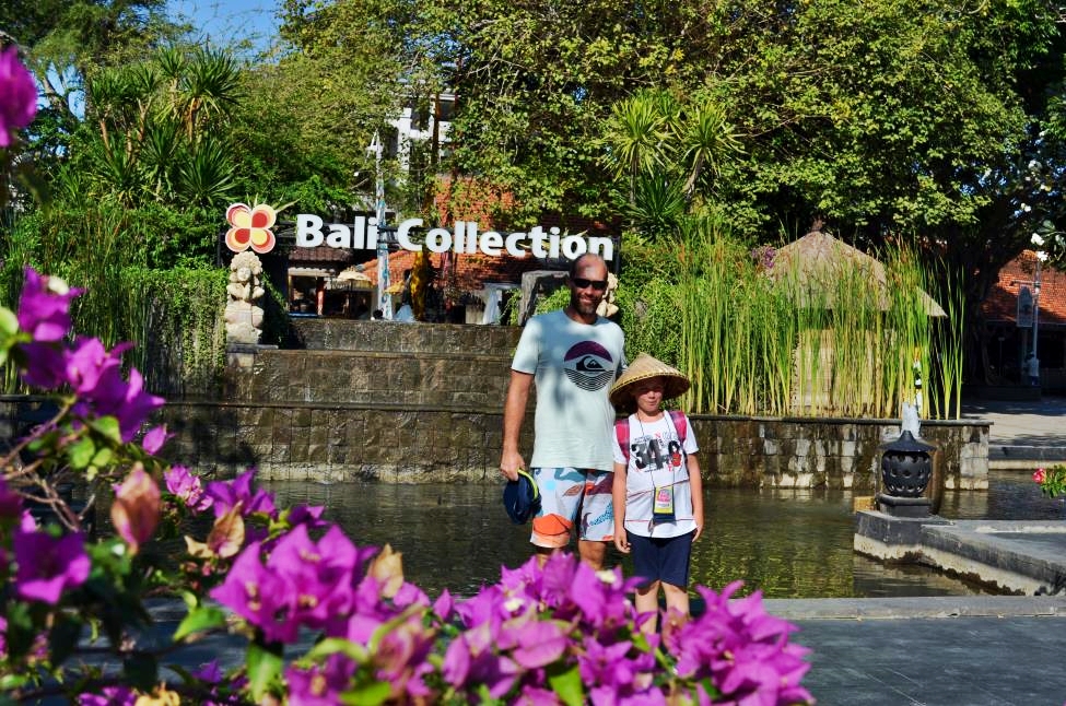 My son and I ready for some shopping at the entrance of Bali Collection mall with flowers and palm trees