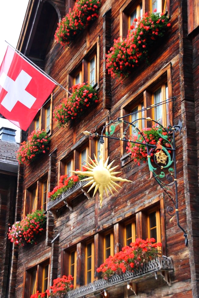 Beautiful facade of a house in Zermatt with red flowers decoration