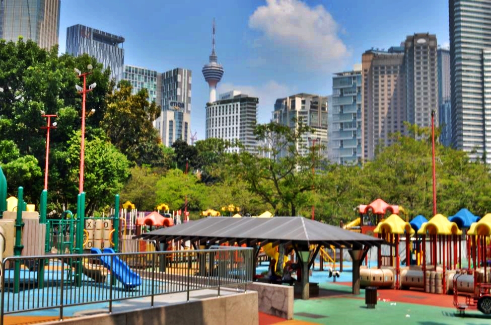 KL Eco Park playground with lush vegetation and skyscrapers in the background
