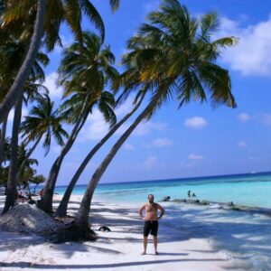 Proudly conquered Maafushi island beach. I am standing on a white sand, next to palm trees and the ocean