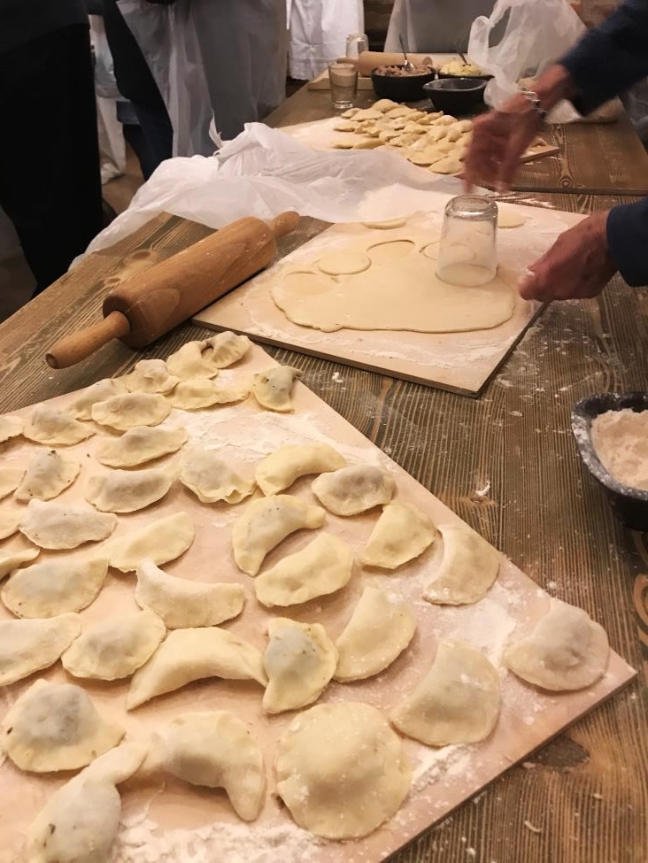 Pierogi making process. Using glass a person cuts off circled pieces of doughs for pierogi