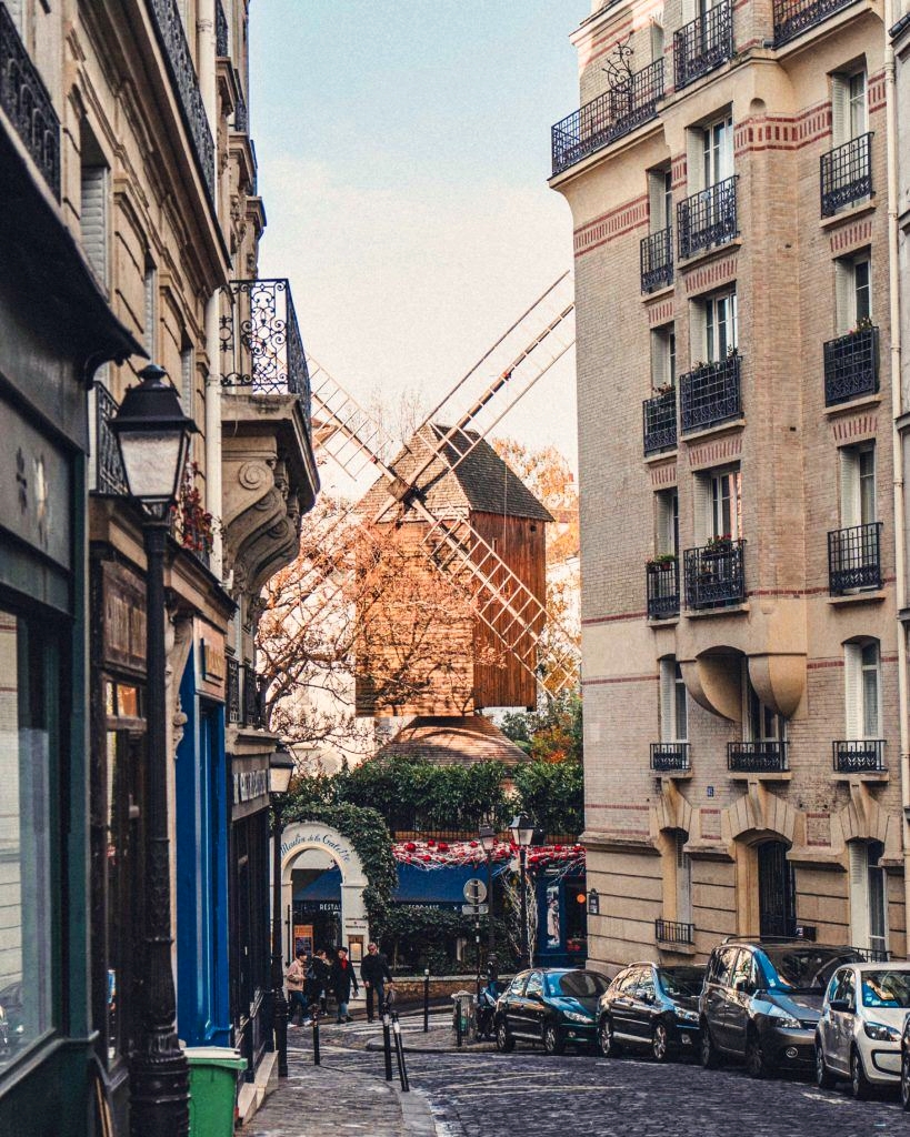 Historic elegant view of Rue Lepic, famous Montmartre street with Galette windmill seen between two buildings