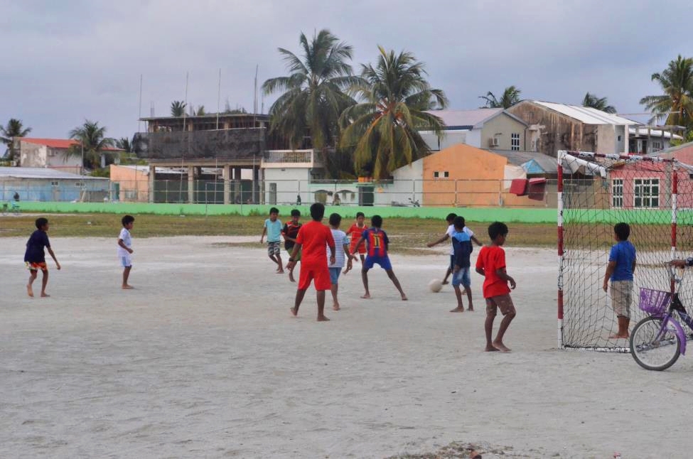 Local kids on Maafushi island playing soccer on a sandy pitch