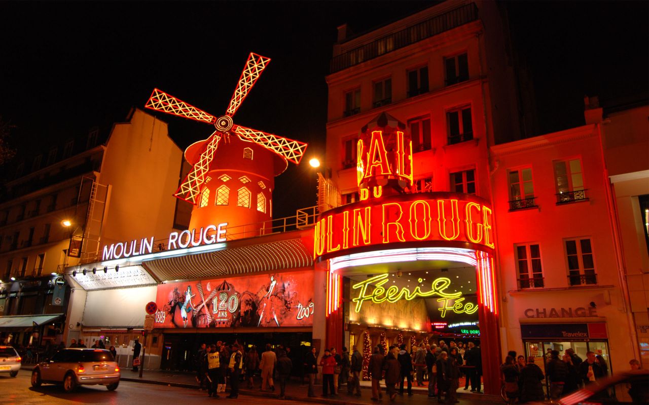 Famous reddish facade of Moulin Rouge Cabaret with iconic red mill lit up