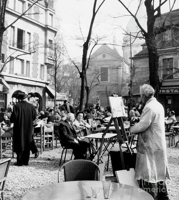 Black and white photo of painter surrounded with people sitting at caffe gardens from 1958.